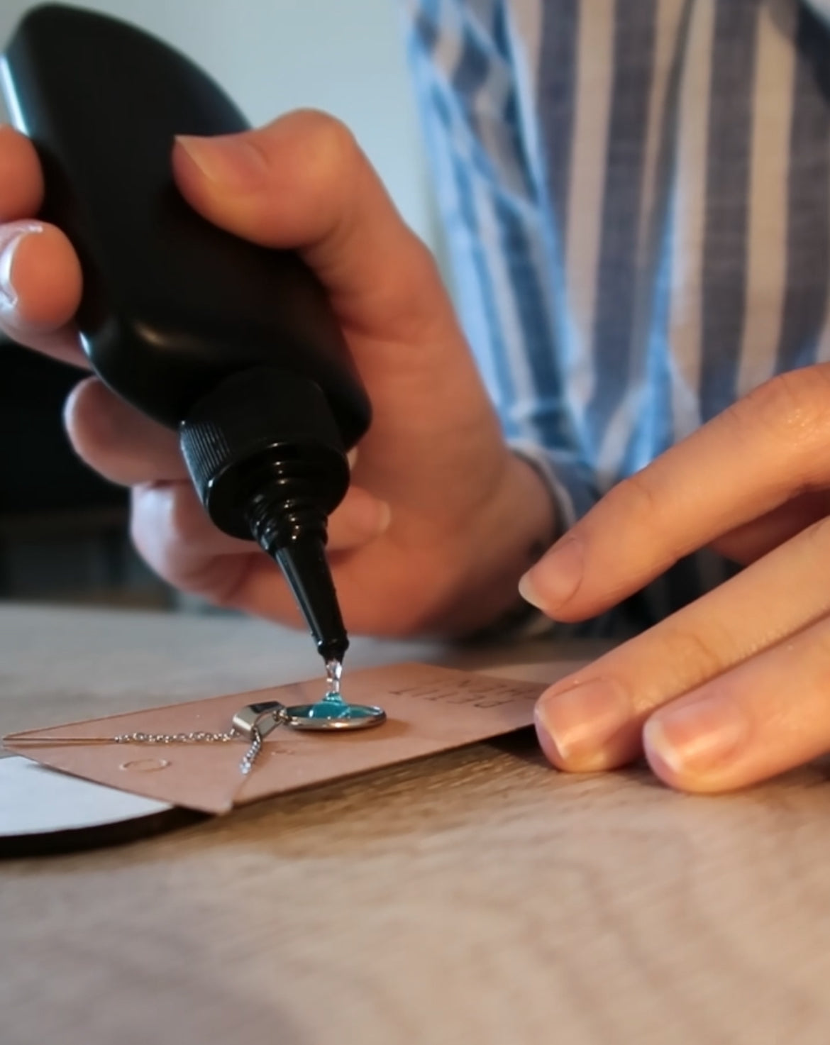 Fabrication artisanale d’un collier souvenir dans l’atelier Petit Chêne : création d’un pendentif en résine et tissu à la main.