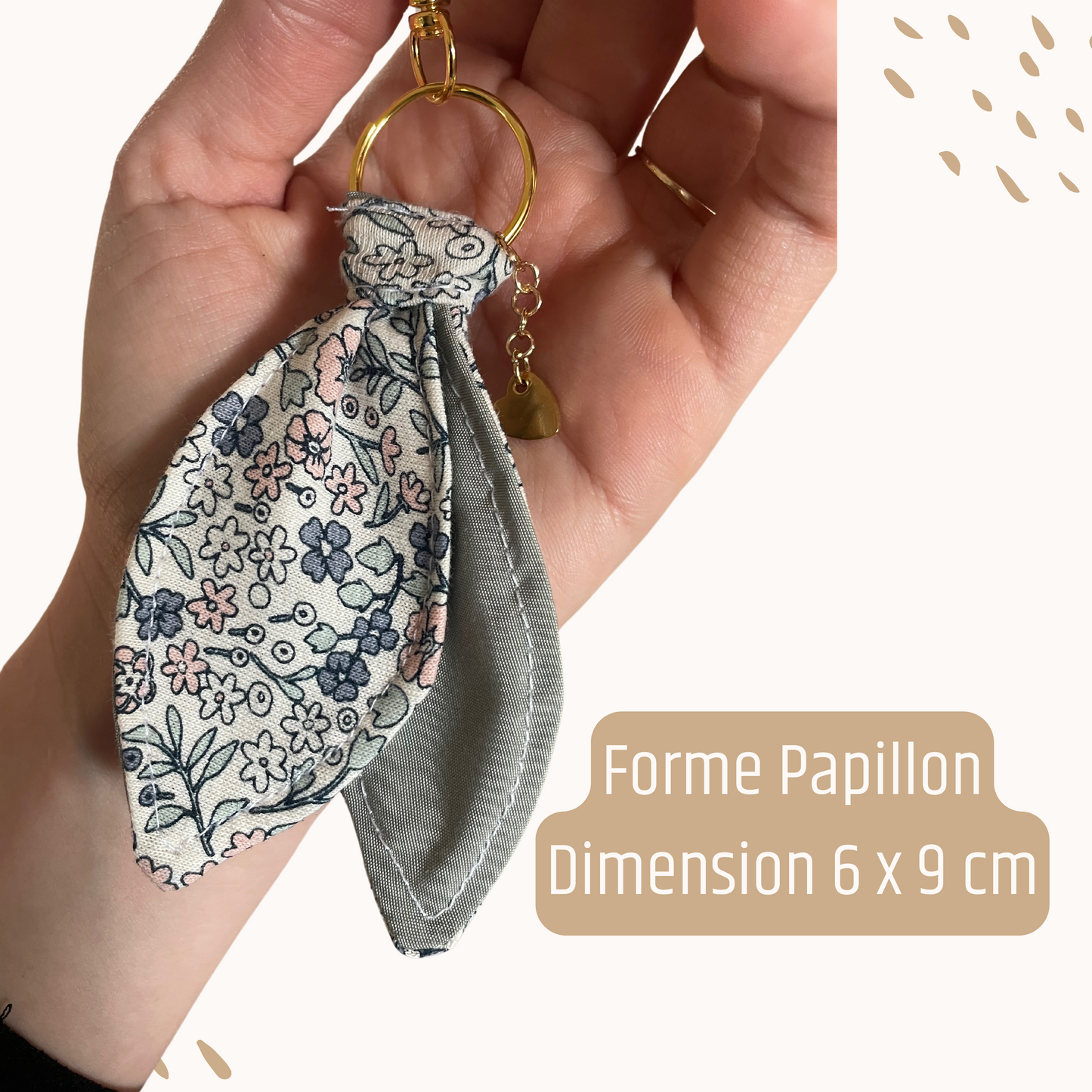 Porte-clés souvenir Petit Chêne, forme papillon, tenu dans une main sur fond clair. Création artisanale et poétique issue de vêtements sentimentaux.